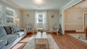 Una sala de estar con un sofá gris, dos sillones, una mesa de centro y una alfombra.
