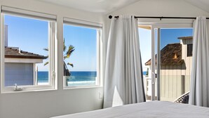 A bedroom with a large bed, two windows, and a view of the ocean and buildings. - The Mission Beach VIP- Luxury Home, 3 Private Decks, 30 steps to the Beach!  (San Diego)