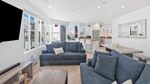 A modern living room with a grey sofa, a wooden coffee table, and a TV mounted on the wall. - The Mission Beach VIP- Luxury Home, 3 Private Decks, 30 steps to the Beach!  (San Diego)
