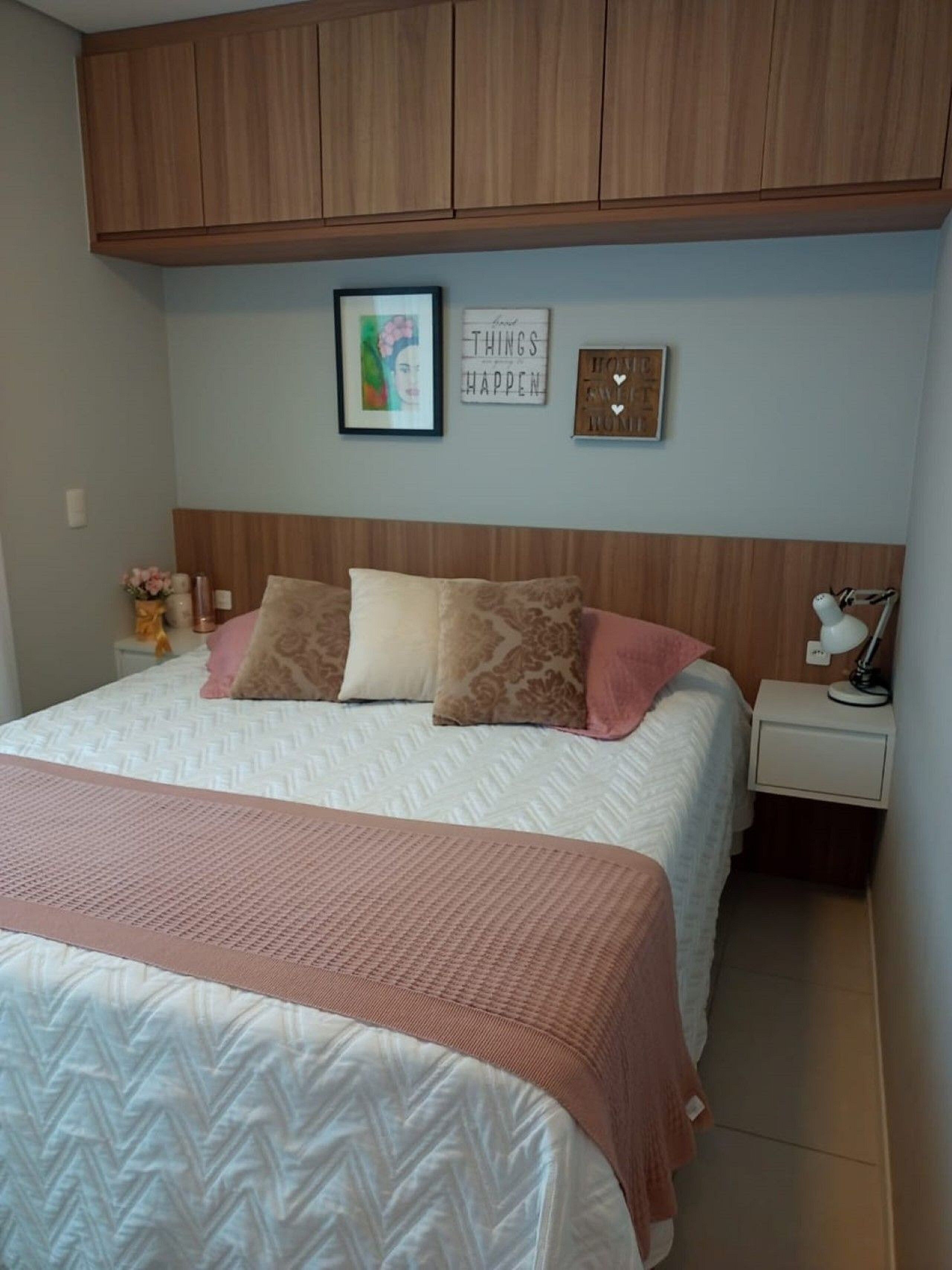 Un dormitorio con cama, mesita de noche, lámpara y adornos en la pared.
