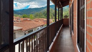 A covered balcony with a view of a town and mountains. - Apartamento Mas (Retiro)
