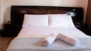 A neatly made bed with white linens and a rolled towel on a textured blanket. - Apartamento Mas (Retiro)