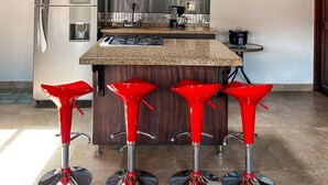 A modern kitchen with a central island, dark wooden cabinets, stainless steel appliances, and red bar stools. - Apartamento Mas (Retiro)