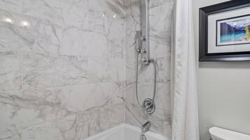 A bathroom with a shower, toilet, and a framed picture on the wall.