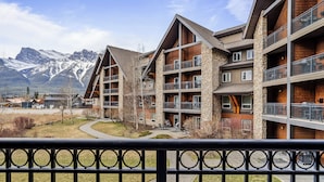 Un hotel a più piani con facciata in pietra e legno, balconi e vista sulle montagne innevate.