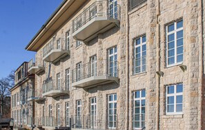 Un edificio de varios pisos de piedra con balcones y ventanas grandes.