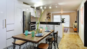 Una cocina moderna con armarios blancos, una mesa de comedor de madera y una encimera negra.