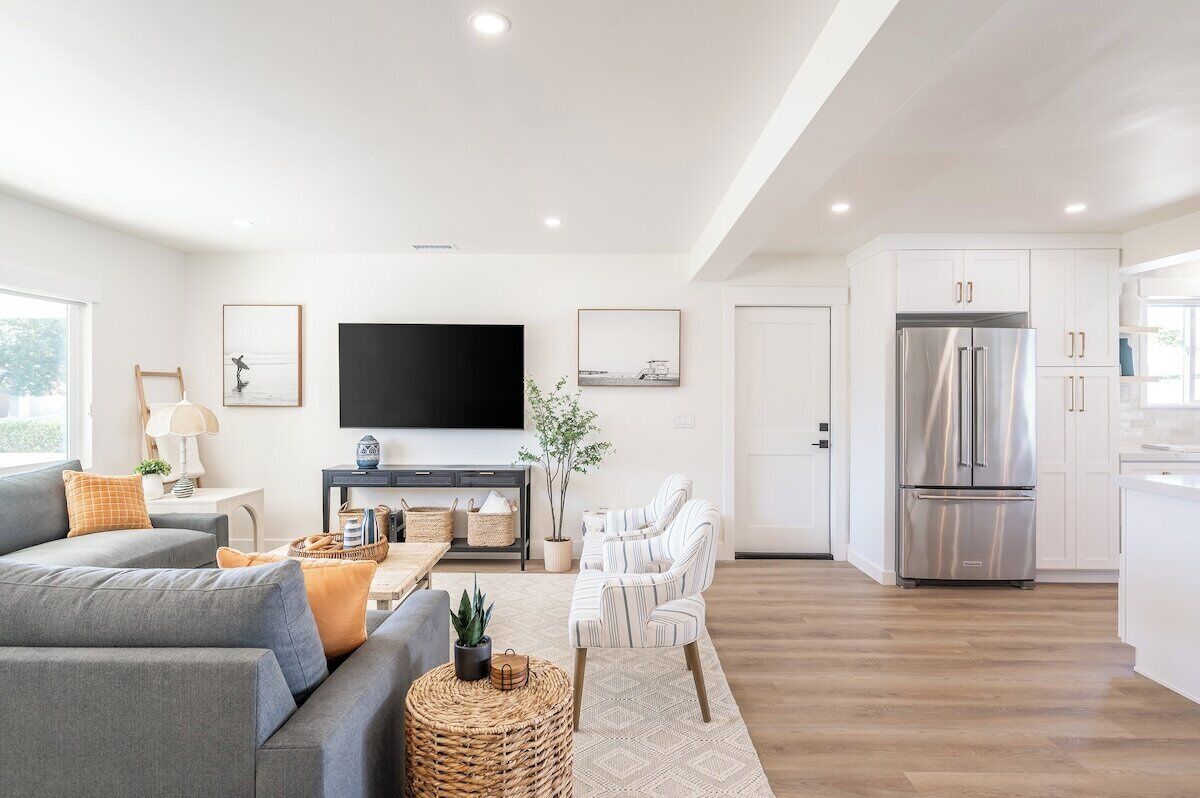 Una sala de estar moderna con un sofá gris, un televisor de pantalla plana y una zona de comedor con una mesa y sillas.