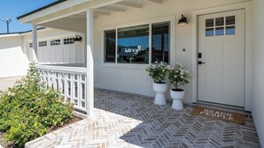 A house with a covered porch, a garage, and a front door with a 'BEACH PEOPLE' mat.