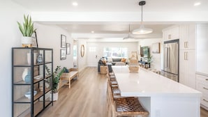 A modern kitchen with a large island, wooden flooring, and white cabinetry.