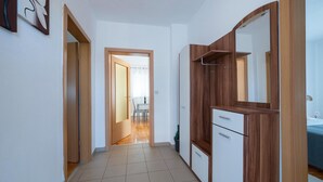 A hallway with a wooden wardrobe, a mirror, and a door leading to a dining area. - Gorgeous apartment in Pula (Pula)