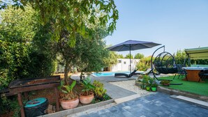 A backyard with a swimming pool, a hanging chair, a table, and potted plants. - Gorgeous apartment in Pula (Pula)