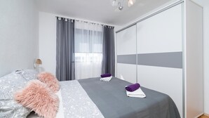 A modern bedroom with a bed, a fluffy pink pillow, a bedside lamp, and a wardrobe. - Gorgeous apartment in Pula (Pula)