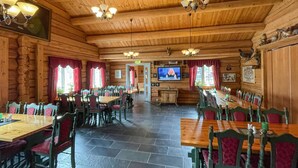 A wooden interior with multiple dining tables and chairs, a television screen, and a stone-tiled floor. - 2 bedroom awesome home in Grue Finnskog (Grue Finnskog)