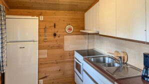 A compact kitchen with wooden walls, a white refrigerator, a stove, and a sink. - 2 bedroom awesome home in Grue Finnskog (Grue Finnskog)