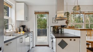 Et moderne køkken med en stor ø, rustfrie hvidevarer og udsigt udad.