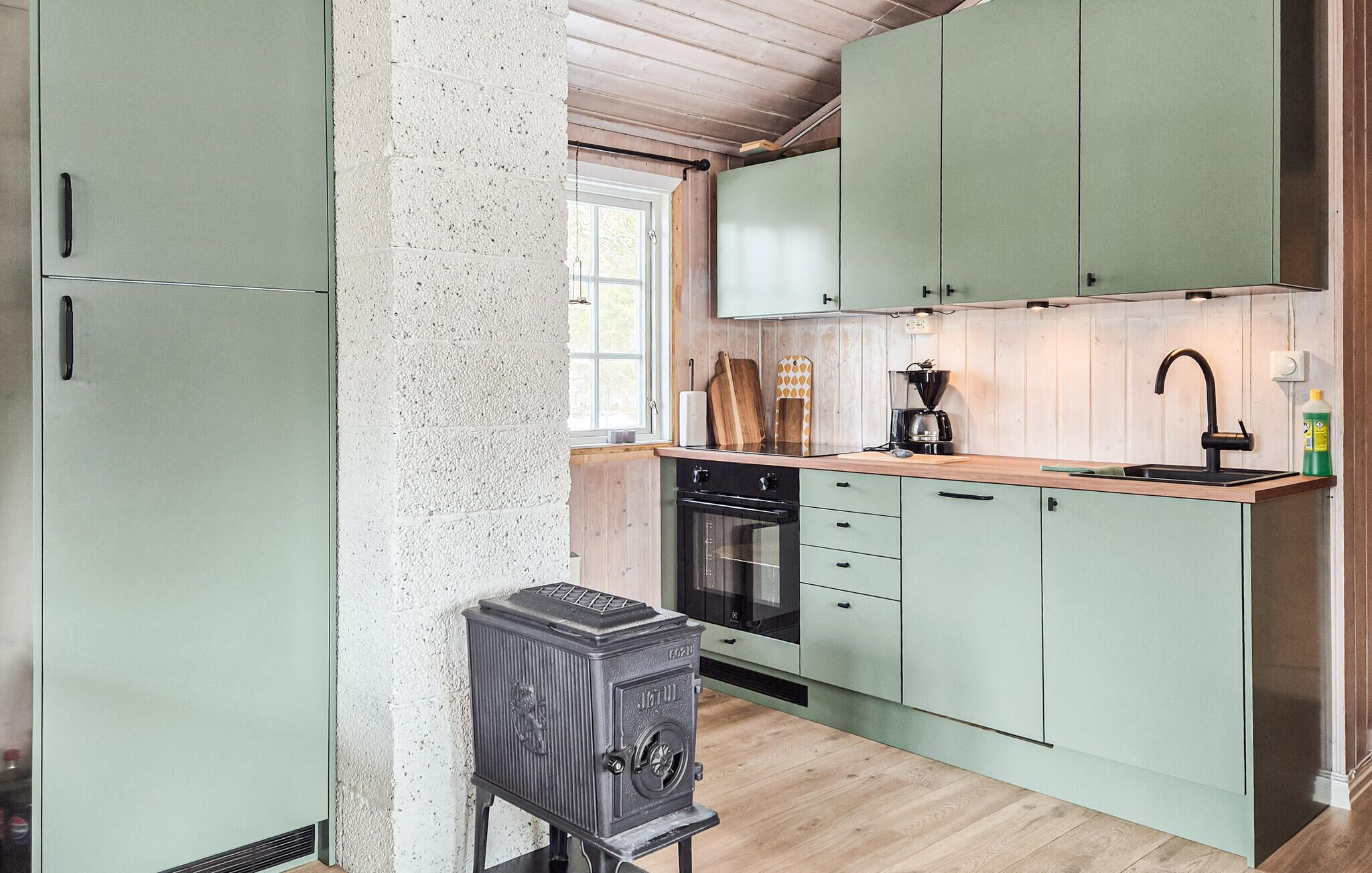 Una cocina con estufa antigua, cafetera y lavabo.