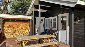Eine Holzterrasse mit Picknicktisch und Holzstapel.