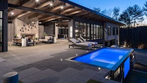 Een modern zwembad met ligbedden en een overdekt terras.