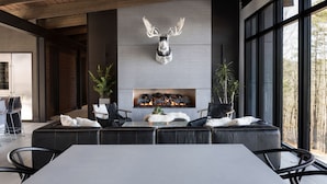 Een modern interieur met een open haard, leren zitmeubels en grote ramen.