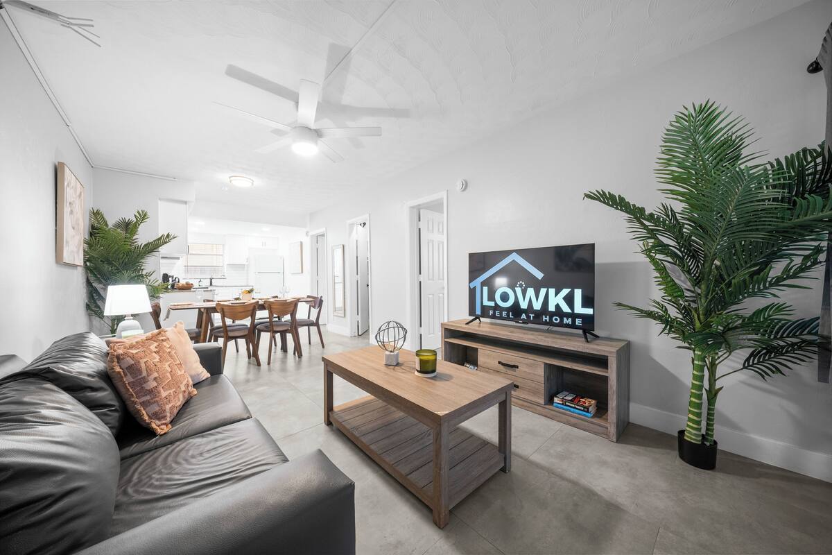 A modern living room with a sofa, coffee table, TV, and potted plants.