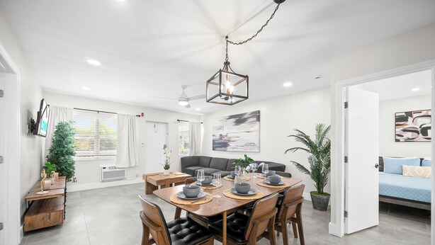 A modern dining area with a wooden table set for four, surrounded by chairs with black leather cushions. - Holiday Park by Lowkl (Fort Lauderdale)
