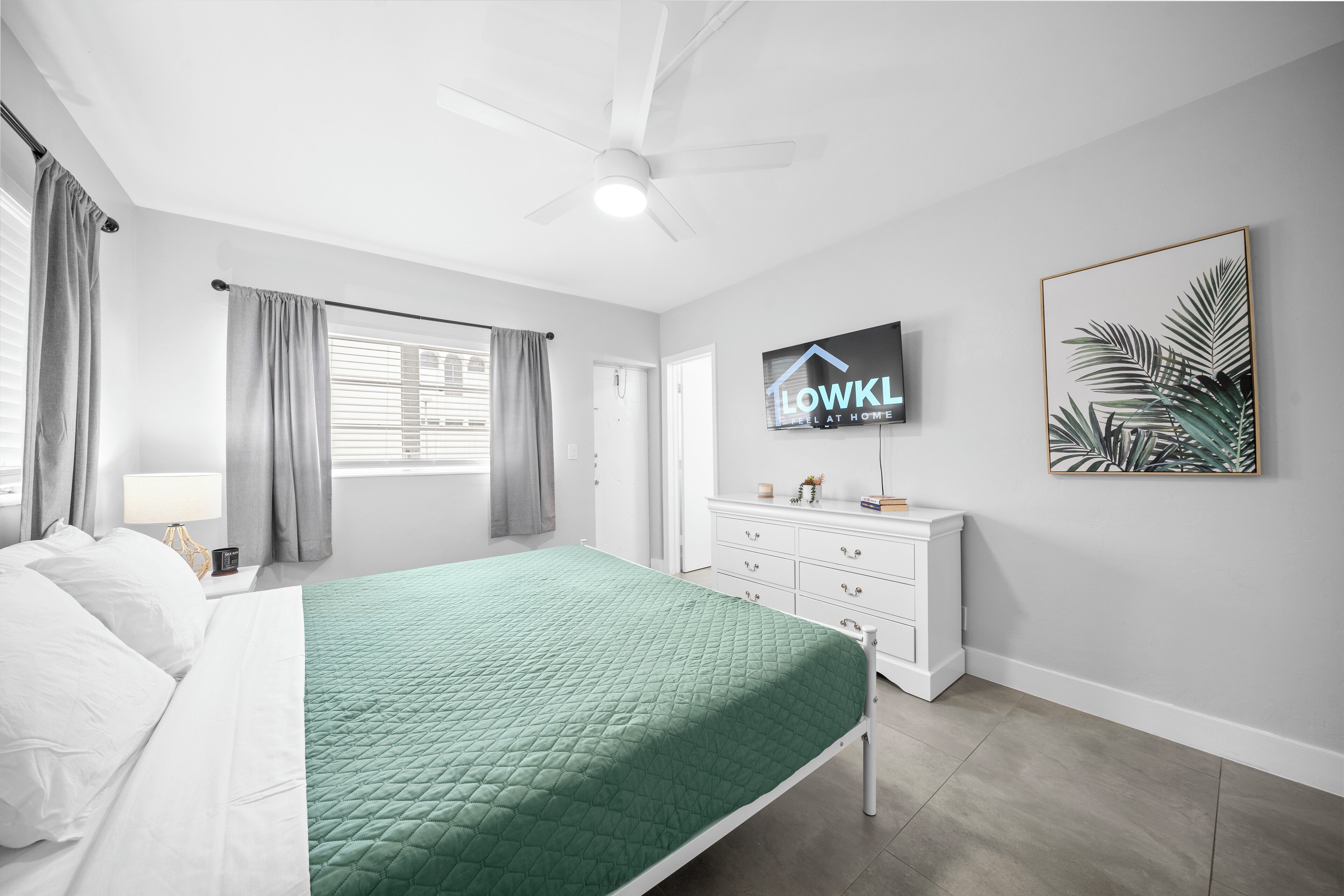 A bedroom with a bed, a TV, a dresser, and a painting.
