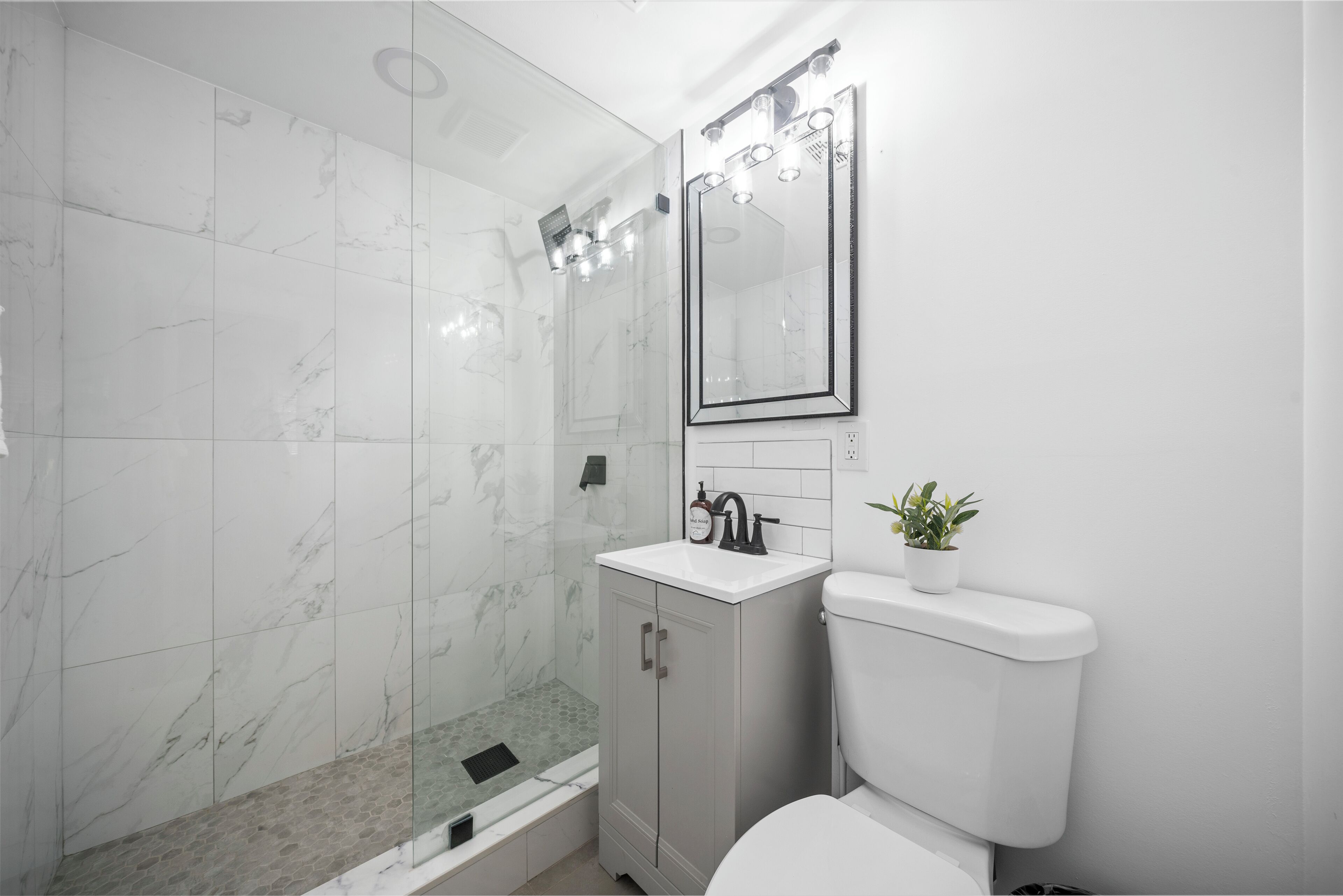 Une salle de bain moderne avec une douche à parois de verre, un lavabo blanc et des toilettes.