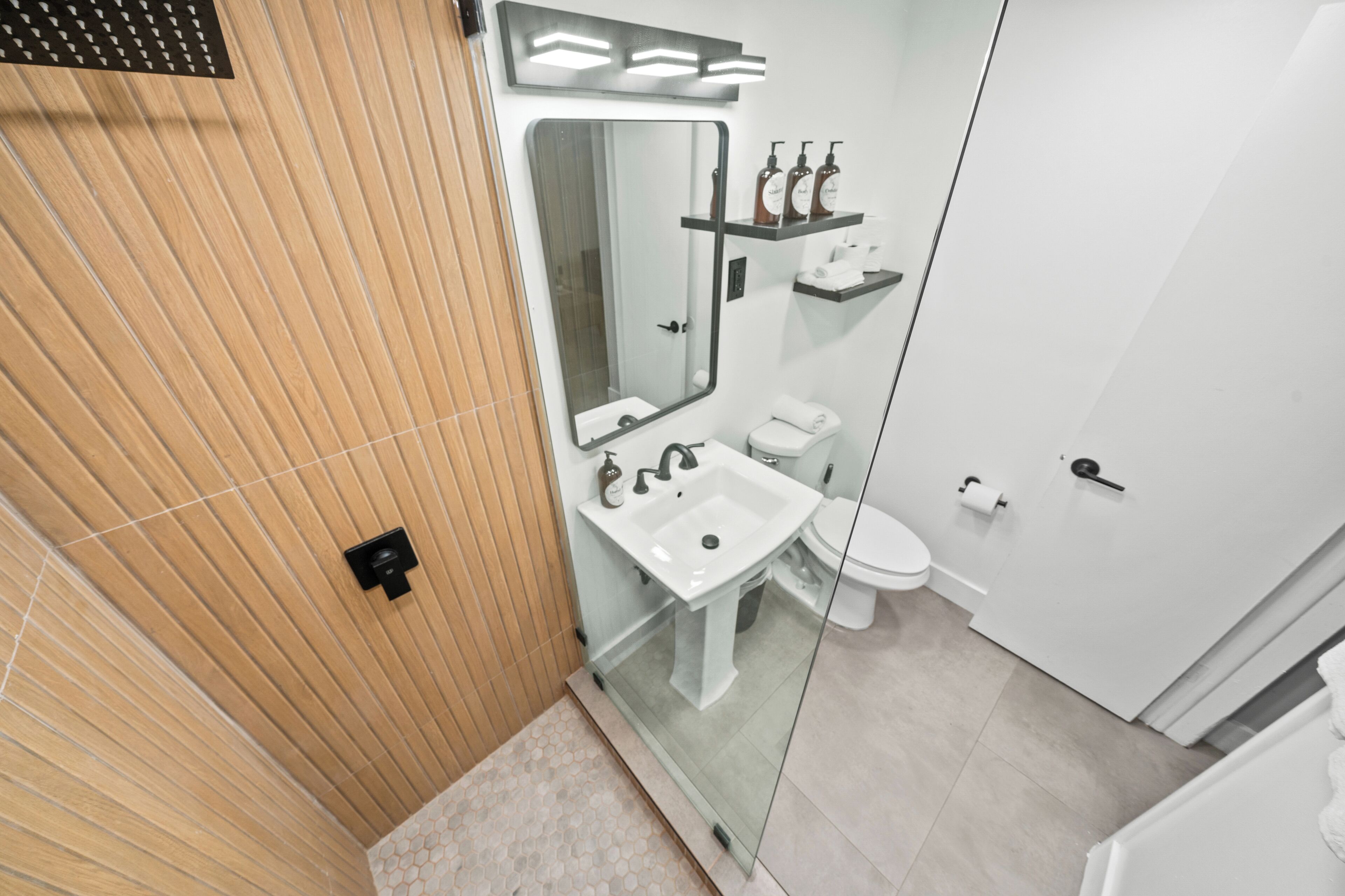 Un bagno moderno con cabina doccia in vetro, lavandino bianco e water.