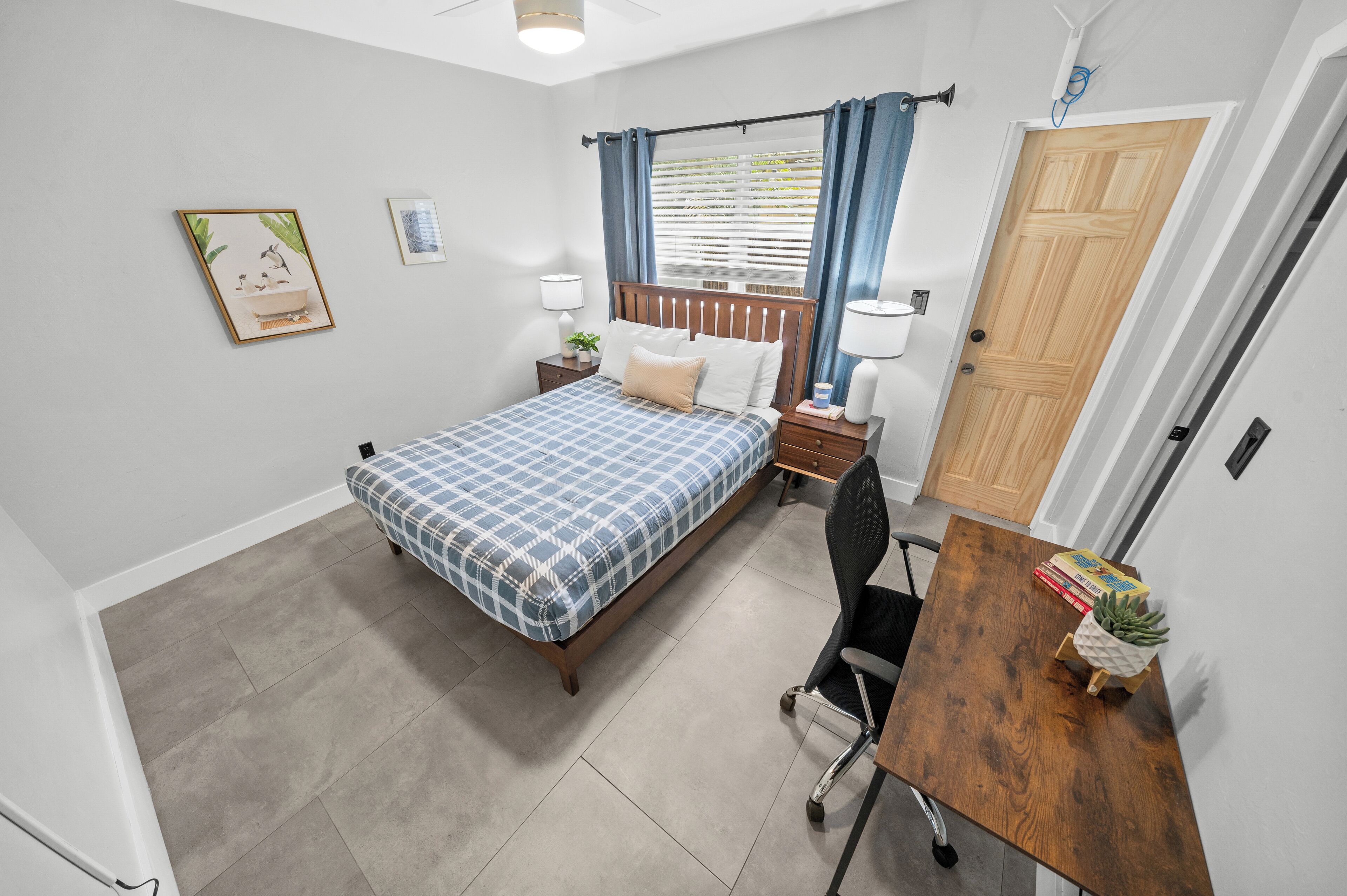 A bedroom with a bed, bedside tables, a desk, and a chair.
