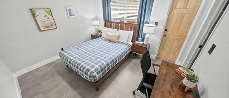 A bedroom with a bed, bedside tables, a desk, and a chair.