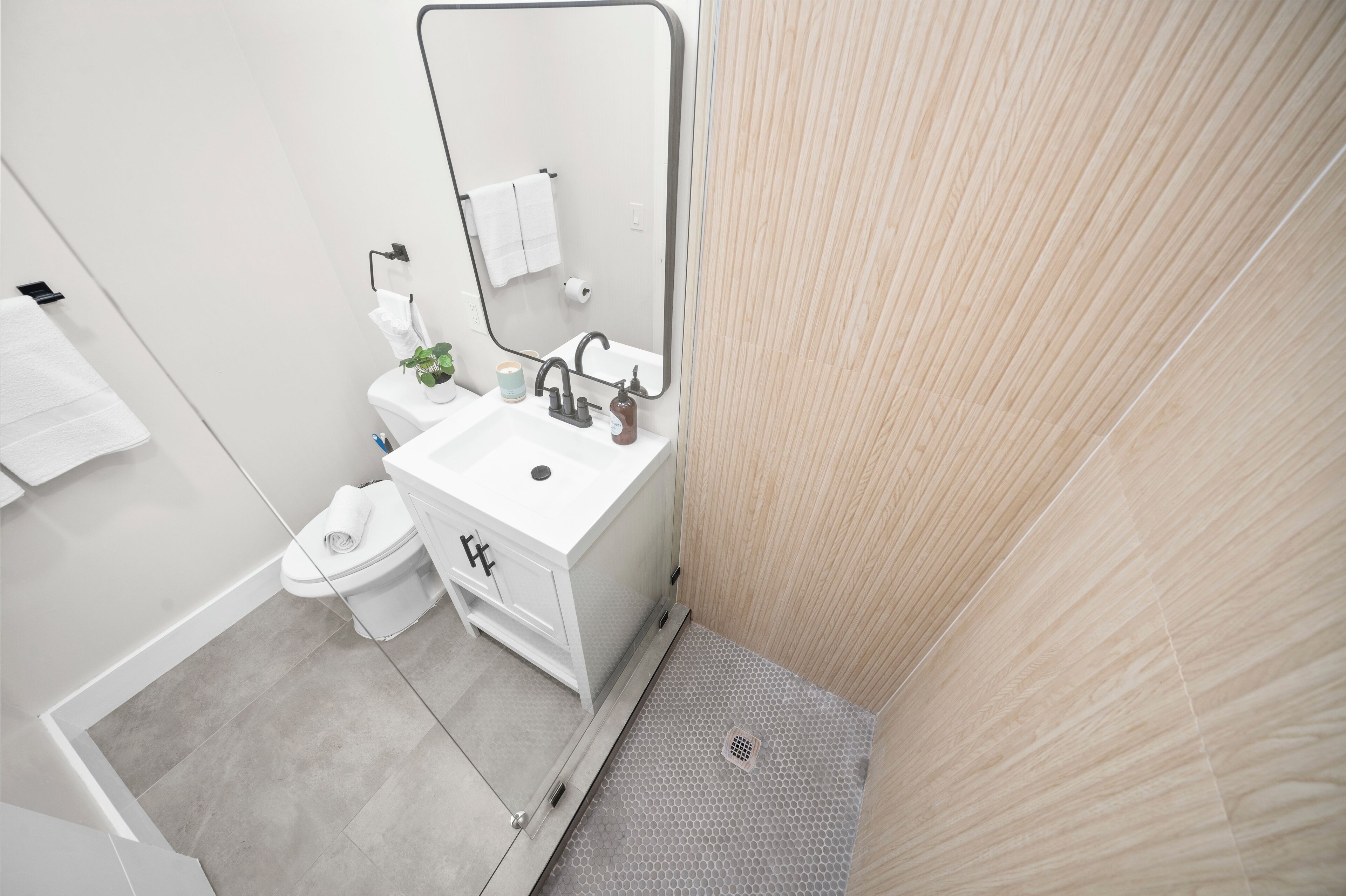 A modern bathroom with a white sink, mirror, and toilet.