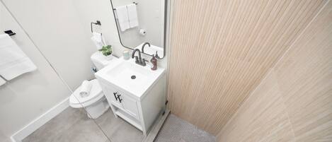 A modern bathroom with a white sink, mirror, and toilet.