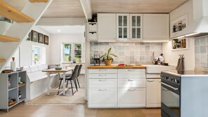 A modern kitchen with white cabinetry, a large island with a sink, and a built-in oven. - Lovely home in Rudkøbing with WiFi (Rudkøbing)