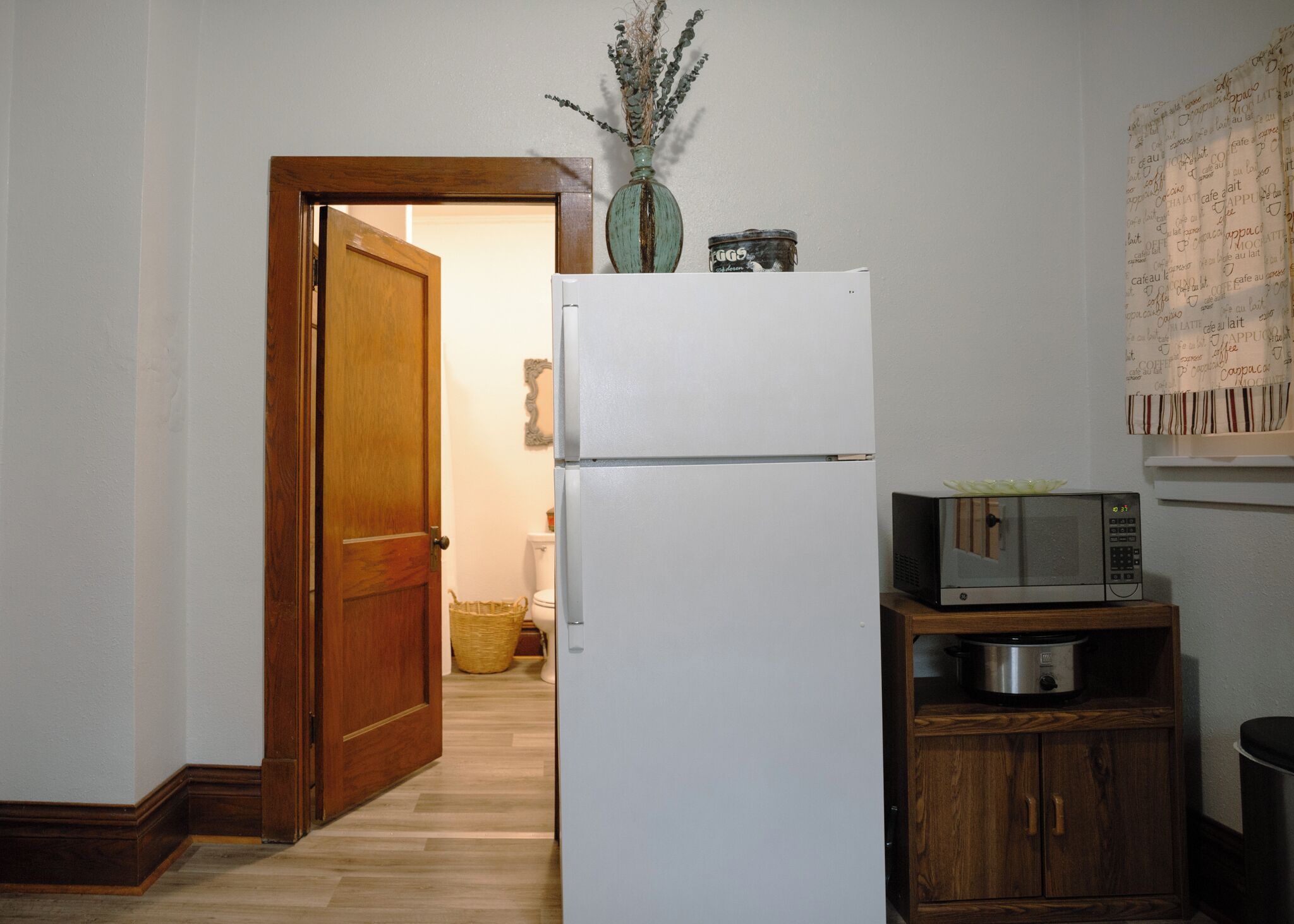 A compact kitchen with a white refrigerator, a microwave, and a wooden cabinet.