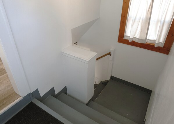 A staircase with a white wall and a window with a wooden frame.