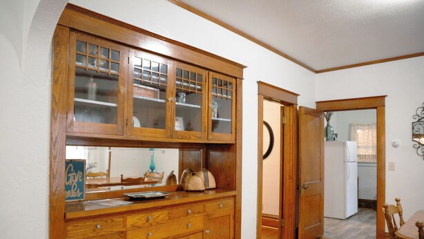 A wooden kitchen with a built-in cabinet and a dining area with a table and chairs. - East Side Motel & Cabins (Mobridge)