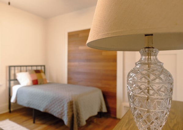 A bedroom with a bed, a lamp, and a wooden door. - East Side Motel & Cabins (Mobridge)