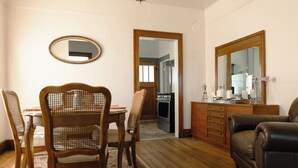 A dining area with a wooden table and chairs, a mirror, and a sofa. - East Side Motel & Cabins (Mobridge)