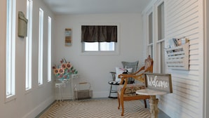 A hallway with a chevron-patterned rug, a wooden chair, a small table, and a 'Welcome' sign on the wall. - East Side Motel & Cabins (Mobridge)