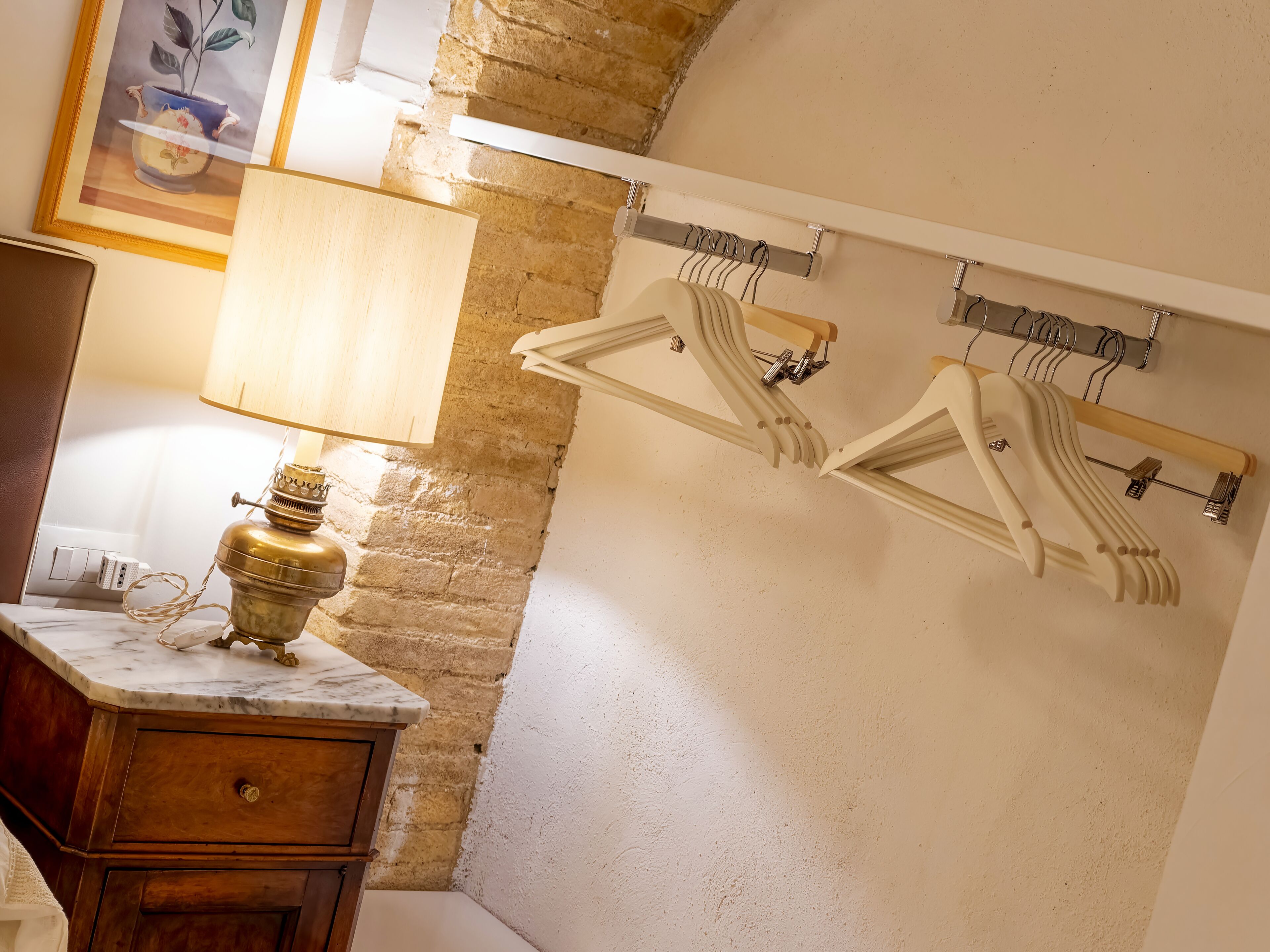 A bathroom with a marble countertop, a brass lamp, a wooden cabinet, and a wall-mounted clothes rack.