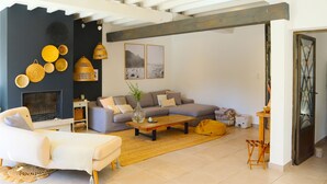 A modern living room with a fireplace, a sofa, a coffee table, and a dining area. - Beautiful home in Pernes-les-Fontaines (Pernes-les-Fontaines)