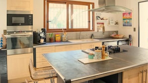A modern kitchen with stainless steel appliances, a large window, and a dining area with a bar stool. - Beautiful home in Pernes-les-Fontaines (Pernes-les-Fontaines)