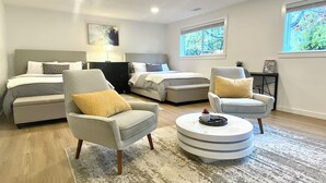 A modern living room with a sofa, armchairs, a coffee table, and a bed with patterned bedding. - 3Bd, 1 bath - Centrally located 15min Airport/Bellevue/Seattle/TopGolf/Hiking (Renton)