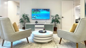 A modern living room with two armchairs, a round coffee table, a flat-screen TV, and two potted plants. - 3Bd, 1 bath - Centrally located 15min Airport/Bellevue/Seattle/TopGolf/Hiking (Renton)