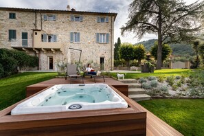 A stone building with a hot tub and a patio area. - Relais Maria Cristina (Chianni)