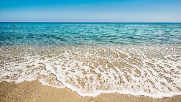 A beach with clear water and a sandy shore.