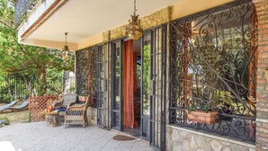A covered outdoor area with wicker furniture, a stone wall, and metal gates.