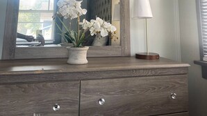 A wooden dresser with a mirror, a potted orchid, and a floor lamp. - The River Green Getaway
 (Fort Wayne)