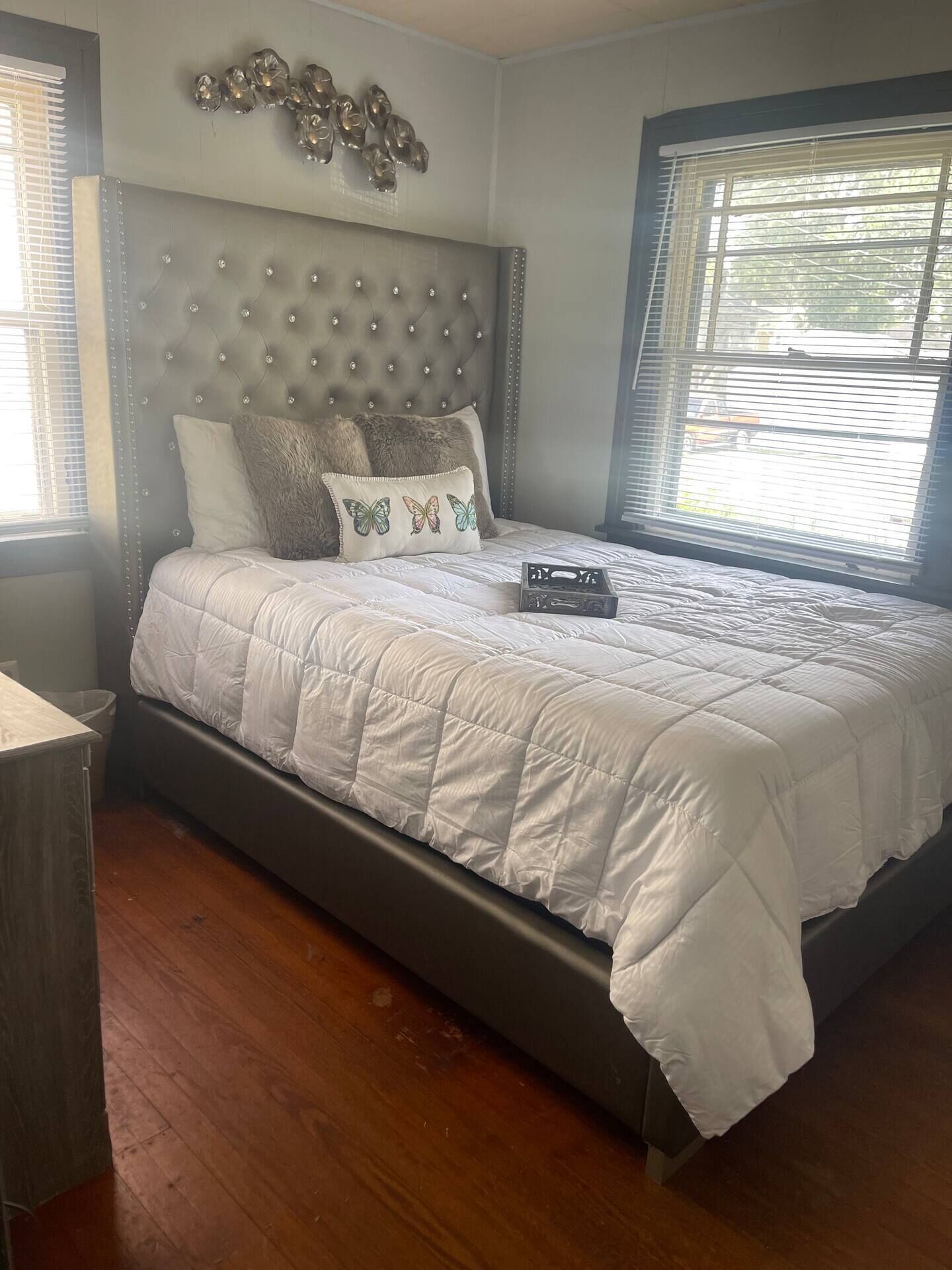 Un dormitorio con cabecera capitonada, edredón blanco acolchado y cojines decorativos.